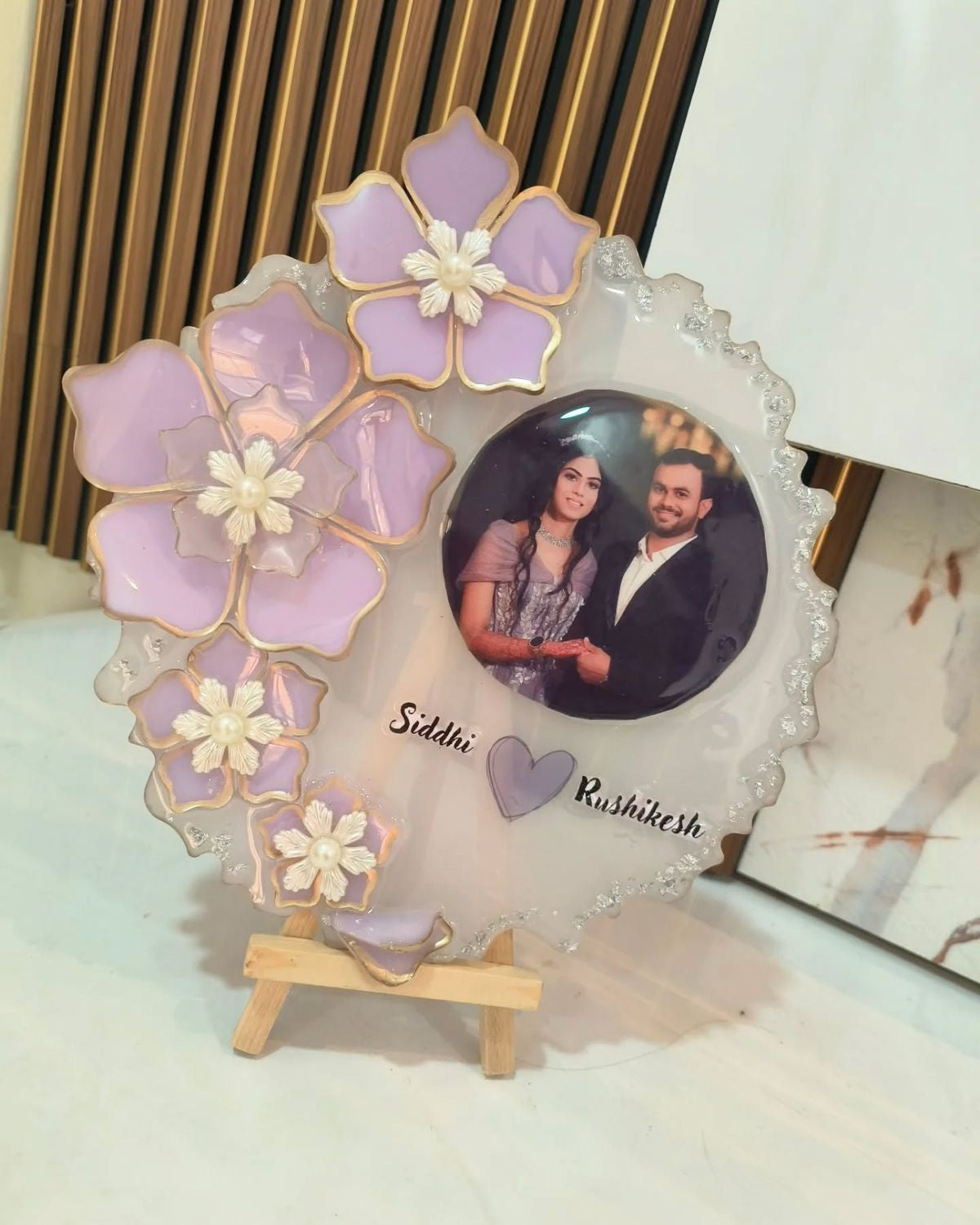 Decorative photo frame with floral design and a couple's portrait on a white surface.