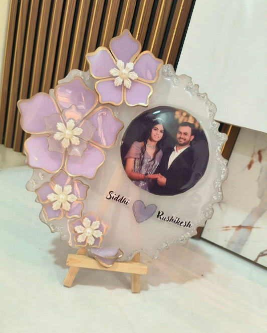 Decorative photo frame with floral design and a couple's portrait on a white surface.