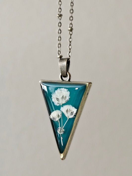 Triangle Resin Necklace with White Dried Flowers on Teal Background